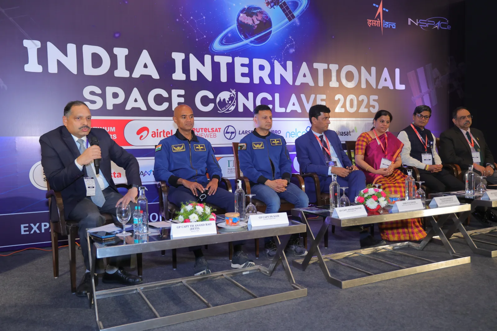 Panel discussion on stage at IISC 2025, with two ISRO astronauts seated among the speakers