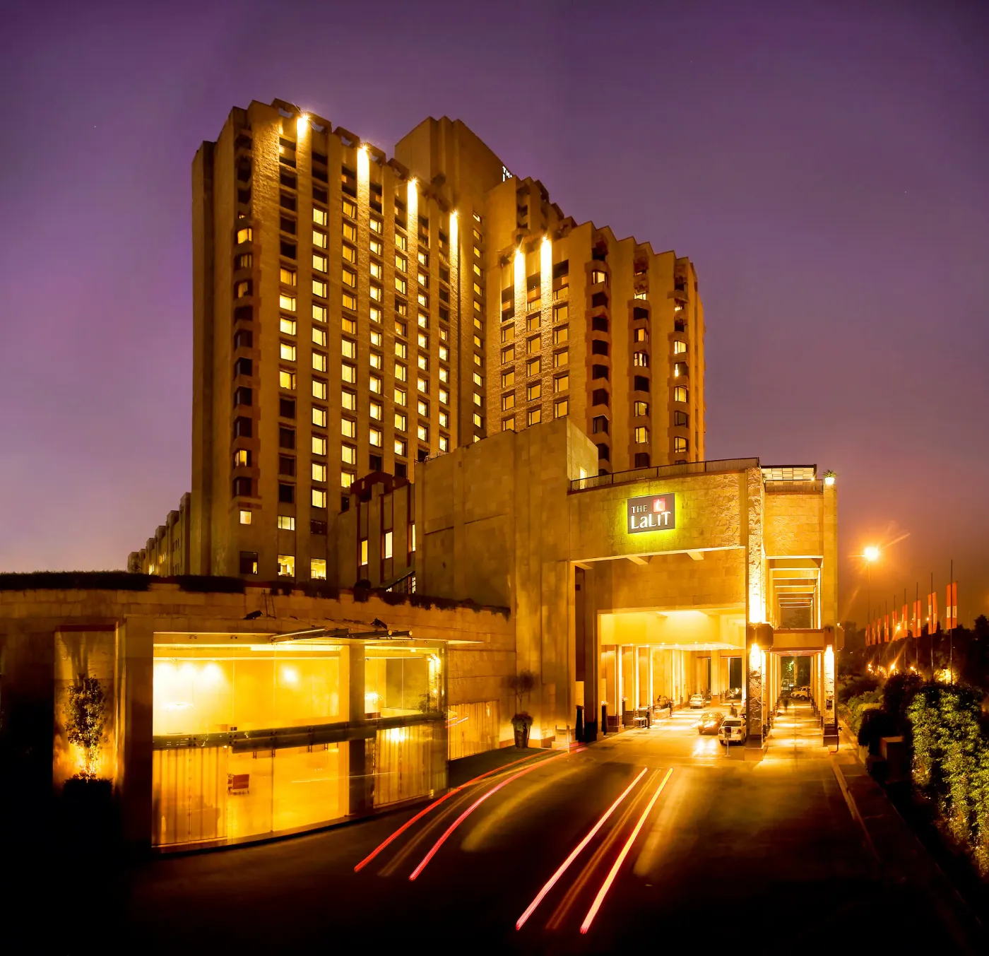 The Lalit New Delhi lit up at dusk, seen from the hotel's entrance driveway